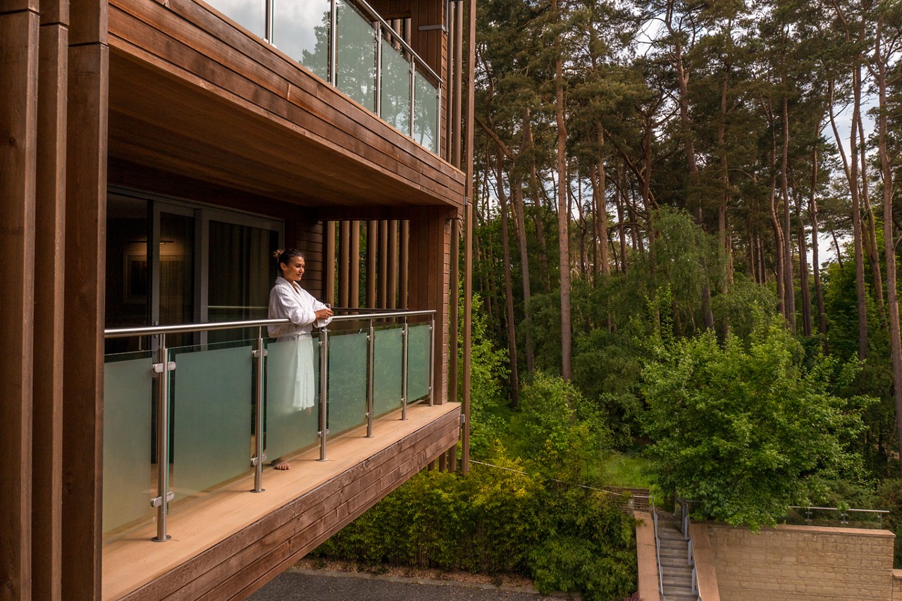 Woman standing on a Spa Suite balcony taking in the forest views.